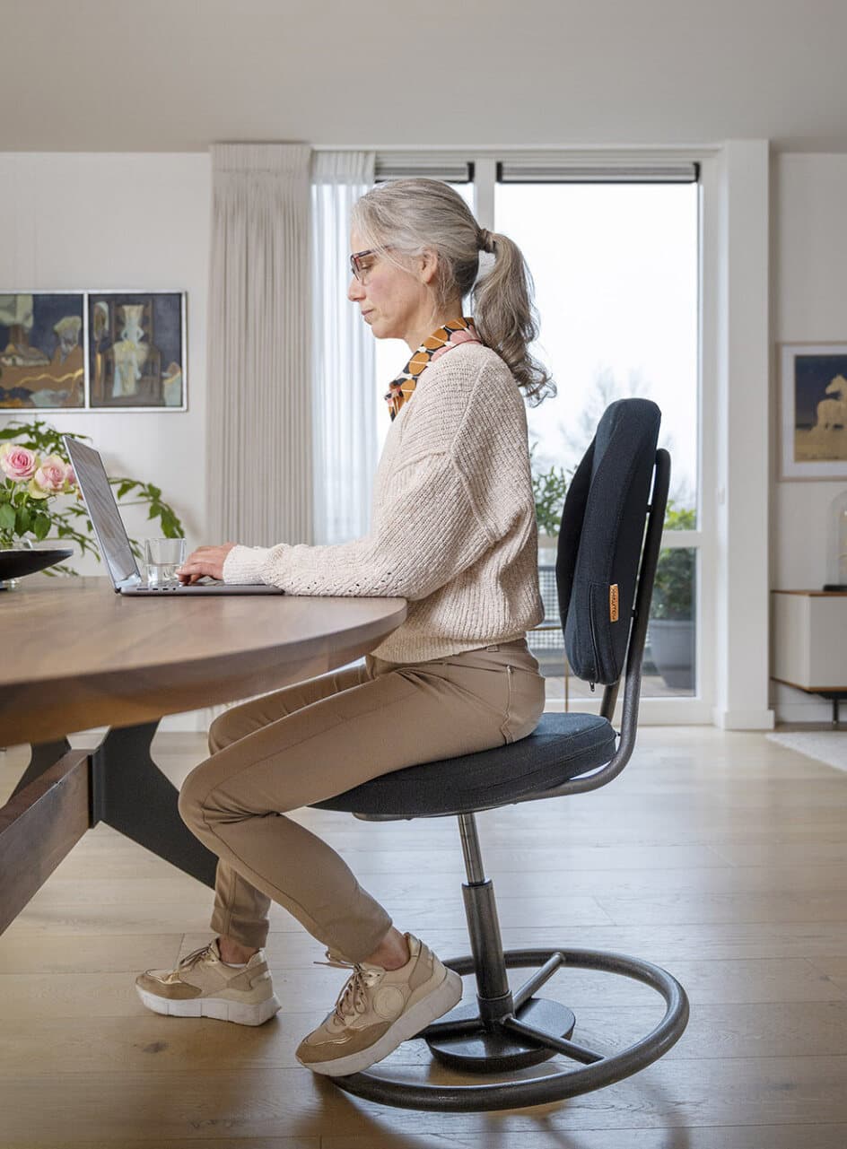 Een vrouw werkt aan een tafel op de FLOWMAXX balansstoel
